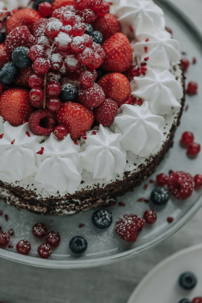 Bolo coberto de suspiro, morangos e frutas vermelhas